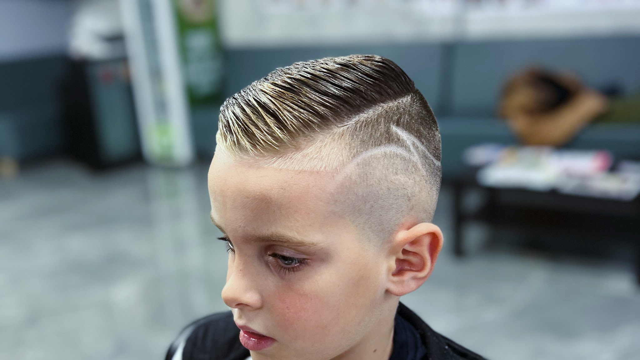 Jongen met een scheiding opzij, strak gekamd, en een lijn in de fade