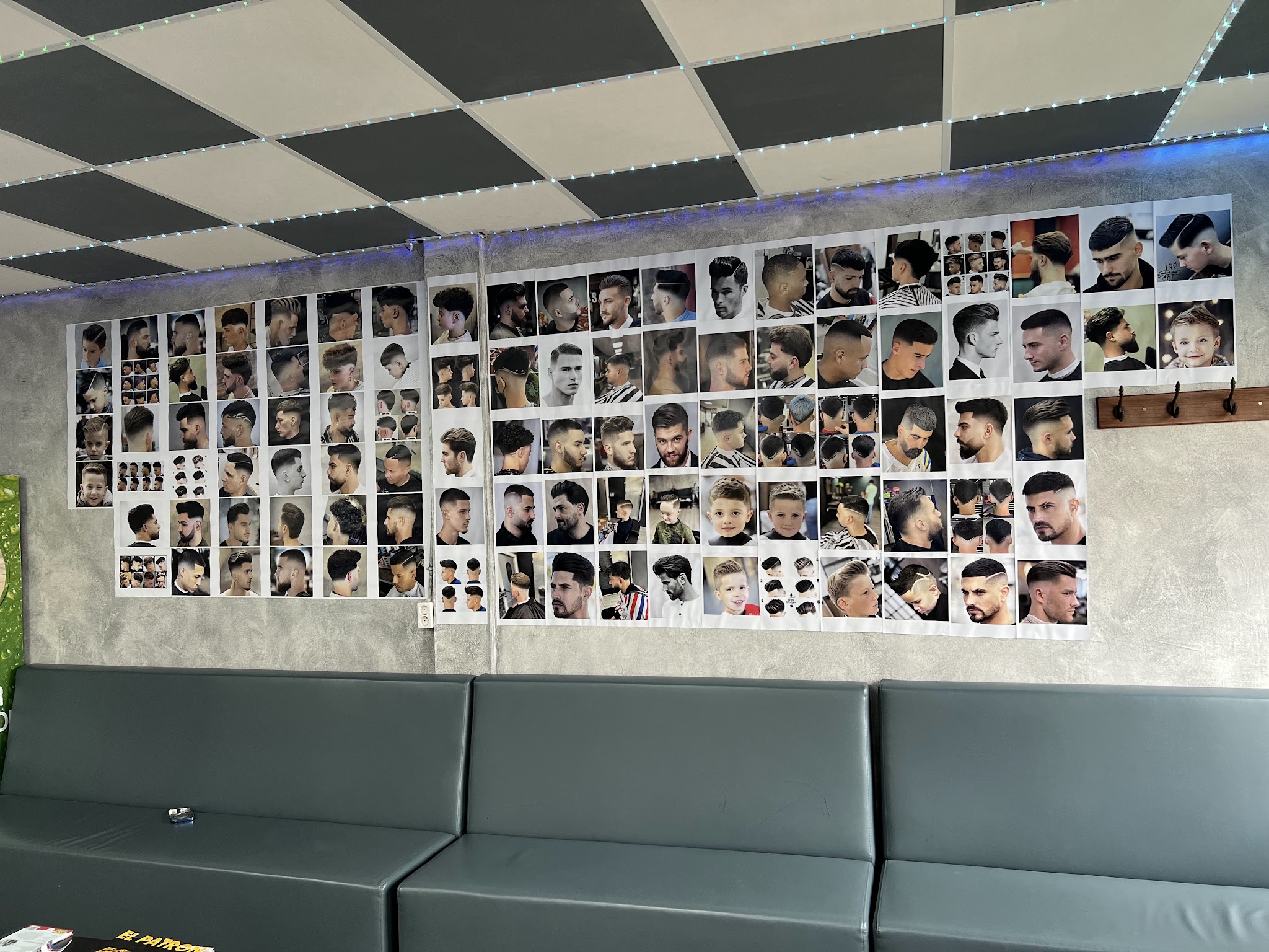 De muur met voorbeeldkapsels boven de wachtbank in de zaak, onder het zwart-grijze dambordplafond